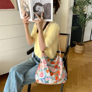 Floral print canvas tote bag on a wicker chair in a warm indoor home setting