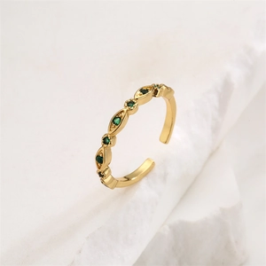 Detail of gold-plated open ring with marquise and round green zircon stones on stone background