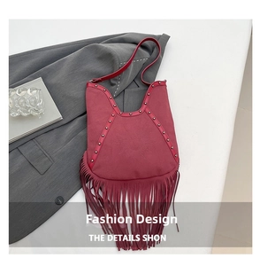 Detail of burgundy fringe shoulder bag with sun embossing and bohemian metal rivets