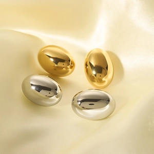 Minimalist 18k gold and silver oval hoop earrings on elegant silk background