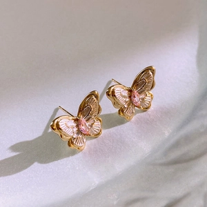 Detailed close-up of gold-plated butterfly earrings with pink cubic zirconia and enamel