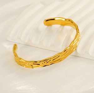 Close-up of golden hammered texture on irregular open cuff bracelet in stainless steel