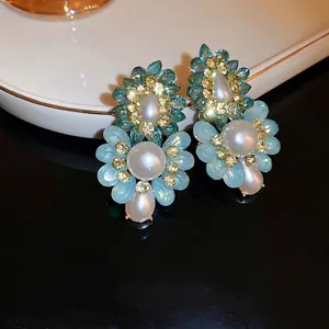 French vintage flower earrings with blue rhinestones and white pearls on a dark mirror background