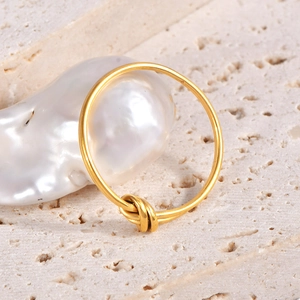 Minimalist knot design 18k gold plated titanium steel ring on textured stone base
