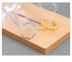 Dettaglio di anelli in oro e argento con trama lavica irregolare e design a onde