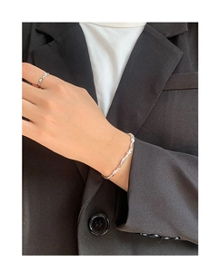 Close-up of minimalist silver woven vine bracelet and textured ring on female model