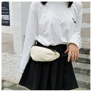 Close-up of a cream canvas waist bag featuring adjustable black strap and zipper detail
