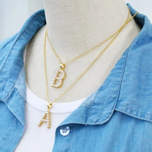 Detailed close-up of gold chain necklaces featuring initials A and B with faux pearls