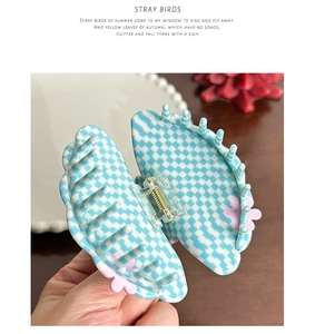 Detail of checkered acetate shark hair claw with pink flower edge and gold spring