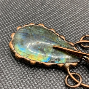 Détail d'un pendentif en labradorite goutte avec reflets bleus et monture en bronze