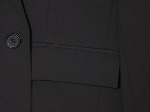 Gros plan d'une veste de costume noire montrant la texture sergée et le bouton