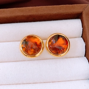 Close-up of vintage amber resin round earrings with gold trim on white display pad