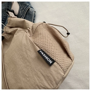 Detailansicht der khakifarbenen Nylon-Beuteltasche mit atmungsaktivem Netz und Fashion-Label