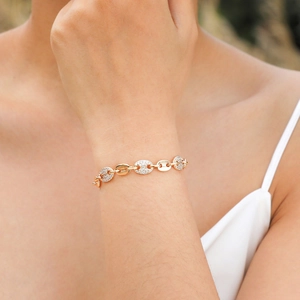 Close-up of golden coffee bean link bracelet with white zircon stones on a female wrist