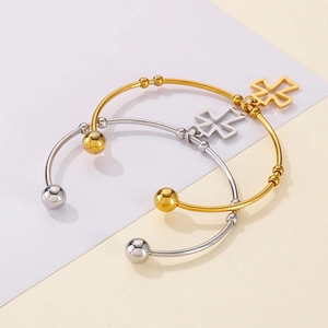Detail view of gold and silver stainless steel open bangles with hollow cross charms