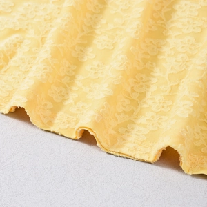 Vue détaillée de la dentelle jaune avec broderies florales complexes et texture en maille