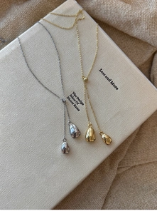 Detail of gold and silver Y-shaped necklaces with metallic pendants on a book