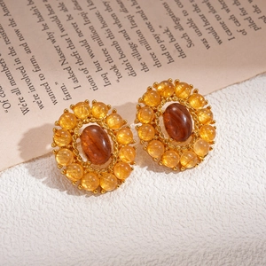 Vintage gold oval agate stud earrings with amber beads on an artistic book background