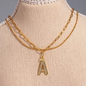 Close-up of a double-layered gold necklace featuring a zircon-studded letter A pendant