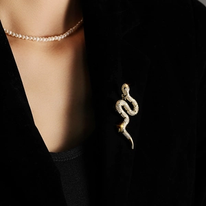 Detailed view of a gold snake brooch set with zircons on a professional black blazer