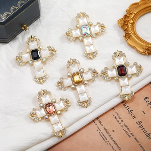 Detail view of gold vintage cross brooches with colorful rhinestones on a classic setup