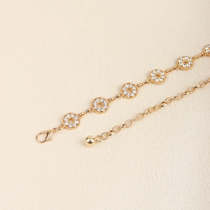 Detailed macro view of golden metal chain belt featuring round sparkling rhinestone links