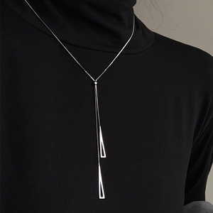 Close-up of a silver triangular Y-pendant sweater chain on black knit fabric