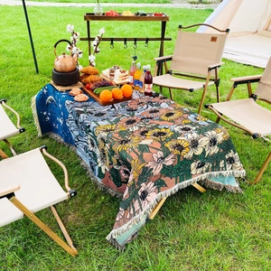 Close-up of woven bohemian blanket with sunflower patterns and fringe on outdoor picnic table