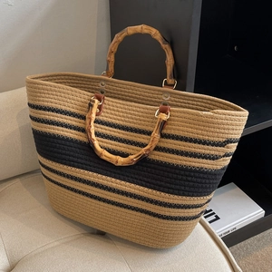Fashionable woven tote bag with bamboo handles and khaki black striped design on sofa