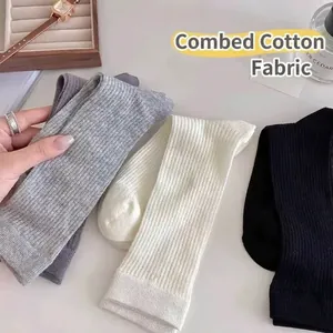 Three pairs of ribbed knit cotton mid-calf socks in black, white, and grey colors