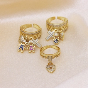 Macro detail of three gold-plated copper rings with zircon pendants on silk fabric