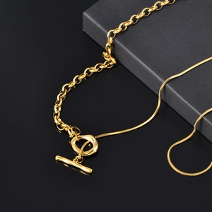 Détail du collier doré avec fermoir à bascule et design asymétrique de chaînes mixtes