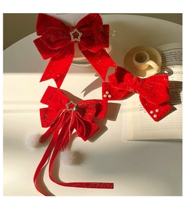 Detailed view of red velvet bow hair clips with pearls, stars, and white pom-poms