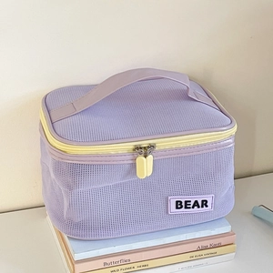 Detail of purple mesh makeup bag with contrast yellow zipper and BEAR label