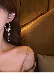 Macro detail of elegant pearl fringe earrings and stud on ear with stone background