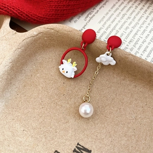 Macro detail of asymmetric lion dance earrings with red enamel and pearl pendants