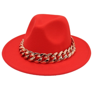 Close-up of bright red fedora hat featuring a chunky polished gold chain decoration