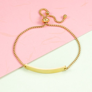Macro view of adjustable gold-plated box chain bracelet with curved rectangular ID bar