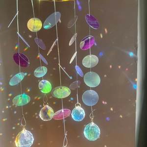 Iridescent sun catcher with crystal ball prism making rainbow light spots on wall