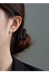 Detail view of vintage French rose earrings with gold stems and white petals on ear
