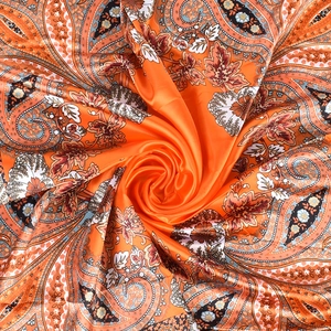 Detailed swirl layout of orange silk scarf with classic paisley and floral patterns