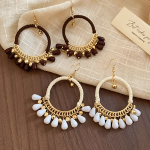 Detail of bohemian drop earrings with thread-wrapped hoops and resin beads on rustic linen