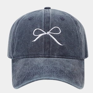 Dettaglio del ricamo a fiocco bianco sul cotone denim lavato del berretto da baseball