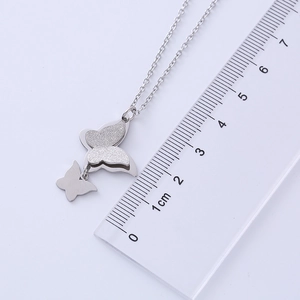 Macro detail of silver-toned double butterfly pendant necklace on a refined O-chain