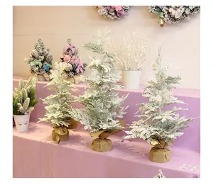 Detailed view of mini flocked Christmas trees with snow effect and burlap bases