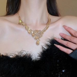 Close-up of sparkling gold drop pendant necklace with champagne crystals on a model