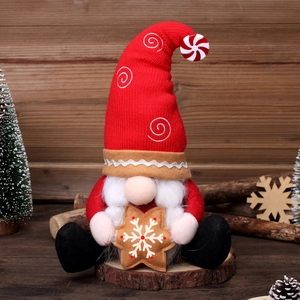 Handmade Christmas gnome plush doll in festive red and white patterns on wood background