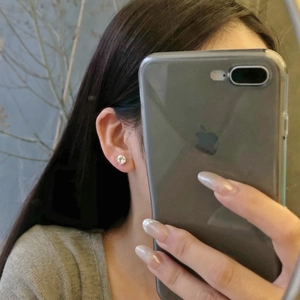 Close-up of a delicate S925 sterling silver stud earring with white zircon on a model