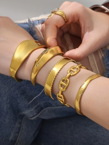 Set de brazaletes rígidos y cadena de eslabones chapados en oro de 18k sobre fondo denim