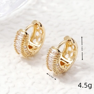 Macro shot of gold zircon earrings with baguette-cut stones and dimensions of 1.4x0.7cm